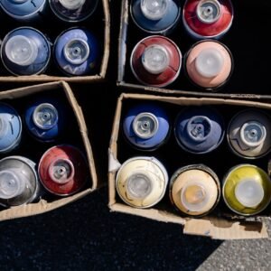 High-angle view of colorful spray paint cans organized in cardboard boxes outdoors.
